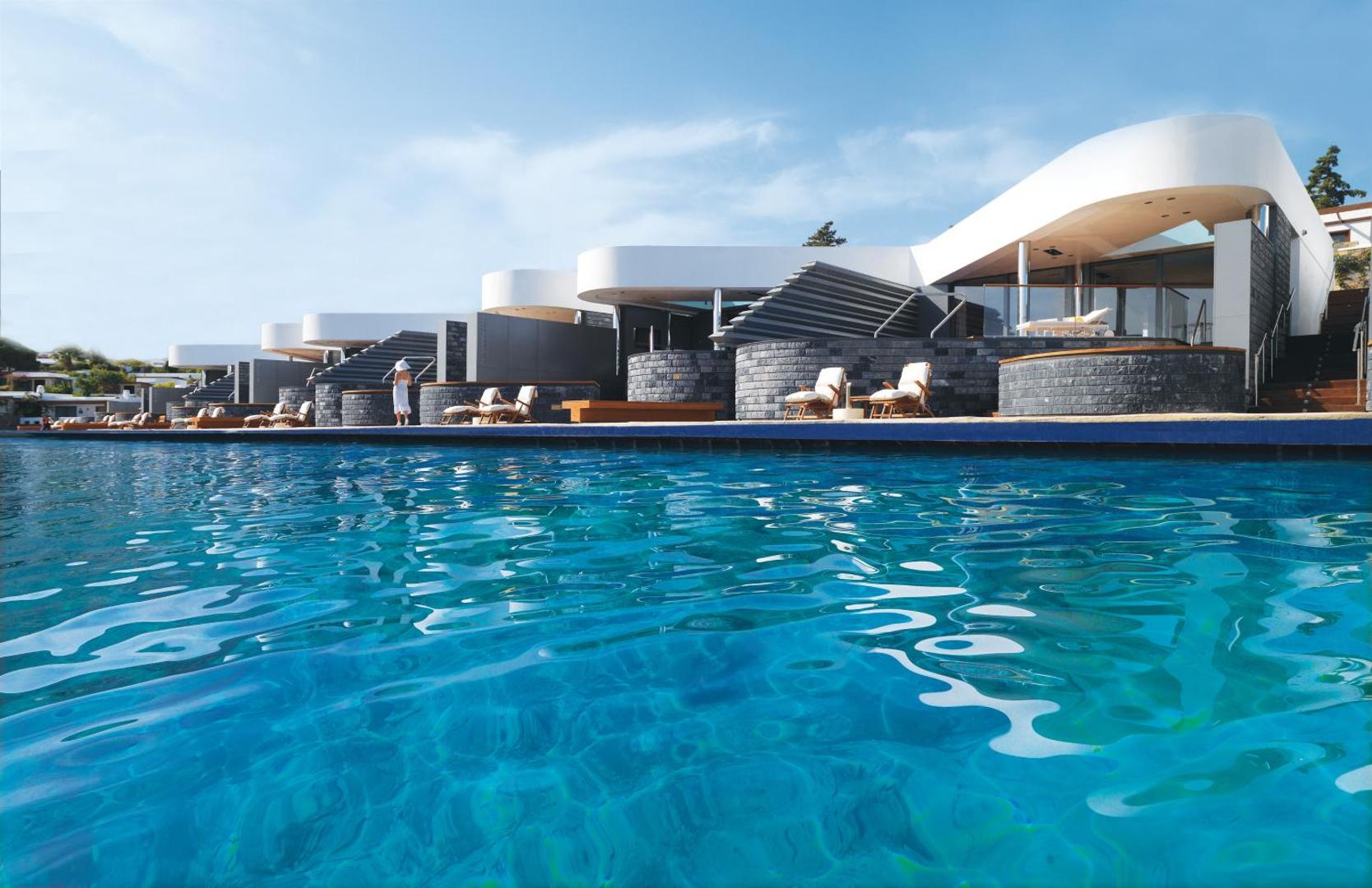 Elounda Beach Hotel And Villas modernie piekrastes bungalo ar sauļošanās krēsliem pie liela āra baseina