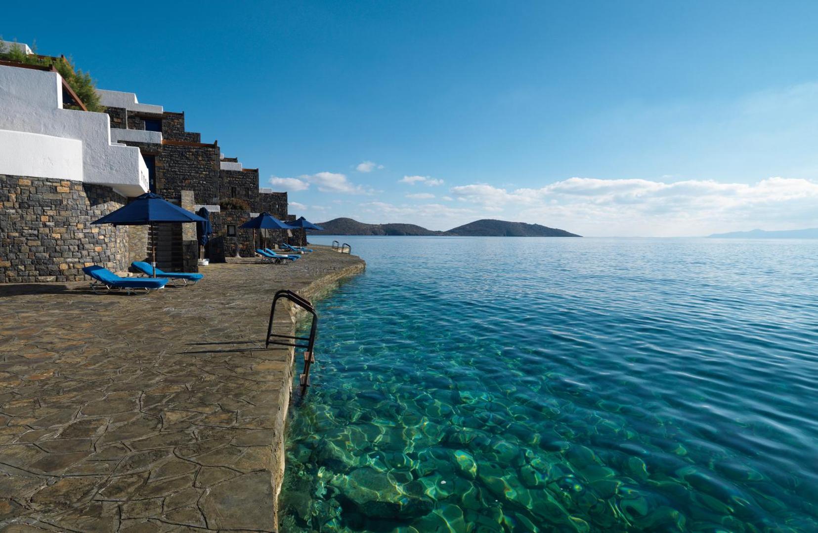 Elounda Beach Hotel And Villas akmens villas tieši pie dzidrā Egejas jūras ūdens Krētā ar sauļošanās terasi un kāpnēm jūrā