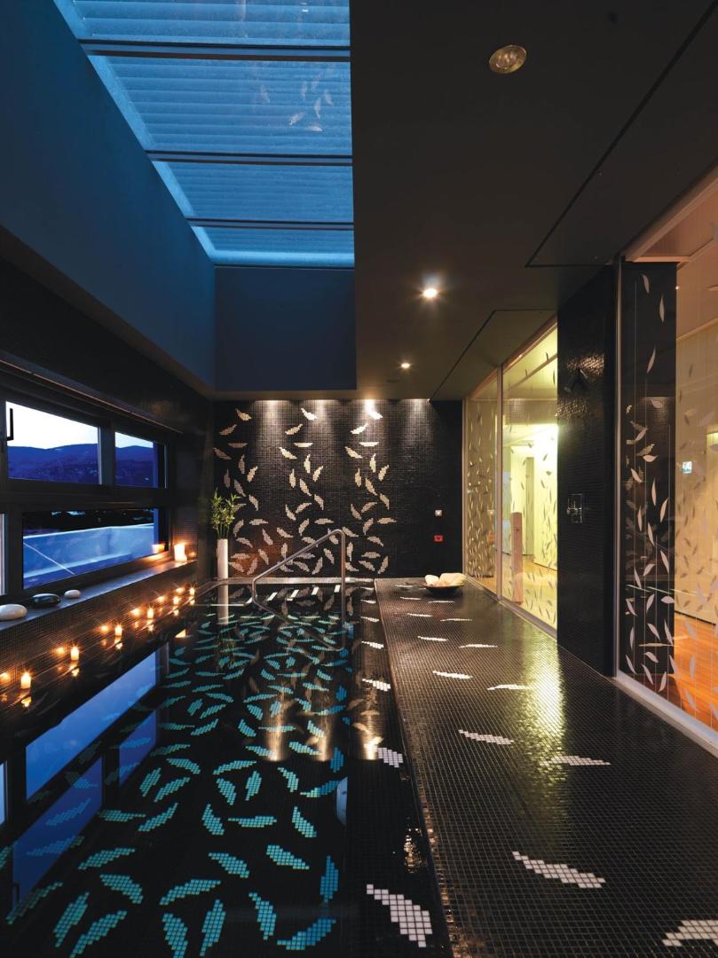 Elounda Beach Hotel And Villas spa zonas iekštelpu baseins ar melnām mozaīkas flīzēm, svecēm un dekoratīvu apgaismojumu vakarā