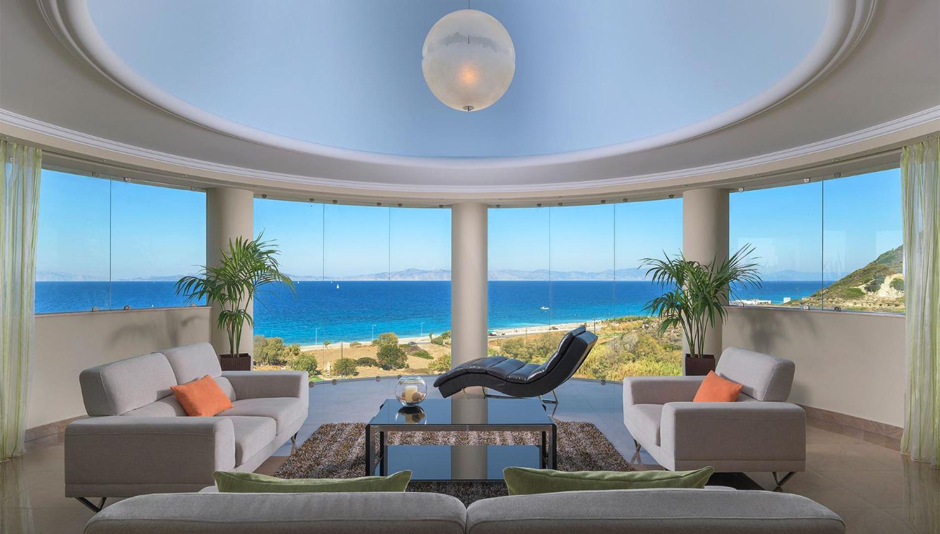 Atrium Platinum Luxury Resort Hotel & Spa atpūtas zona ar panorāmas logiem, dīvāniem un skatu uz piekrasti Rodas salā.