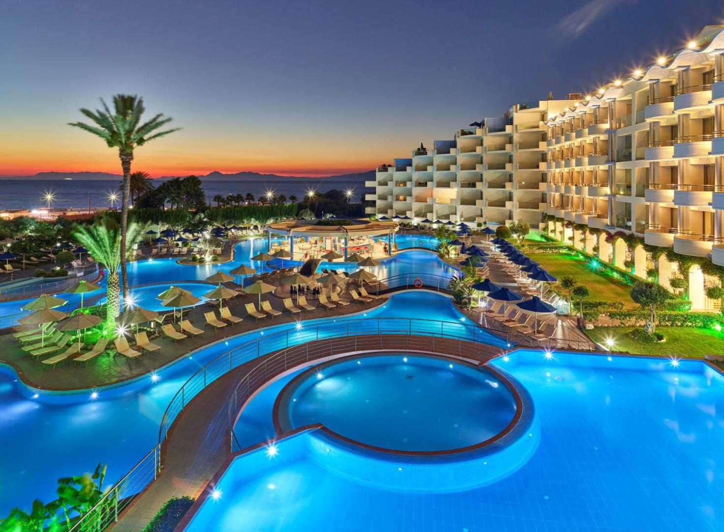 Atrium Platinum Luxury Resort Hotel & Spa vakara panorāma ar izgaismotiem baseiniem un viesnīcas fasādi Rodā