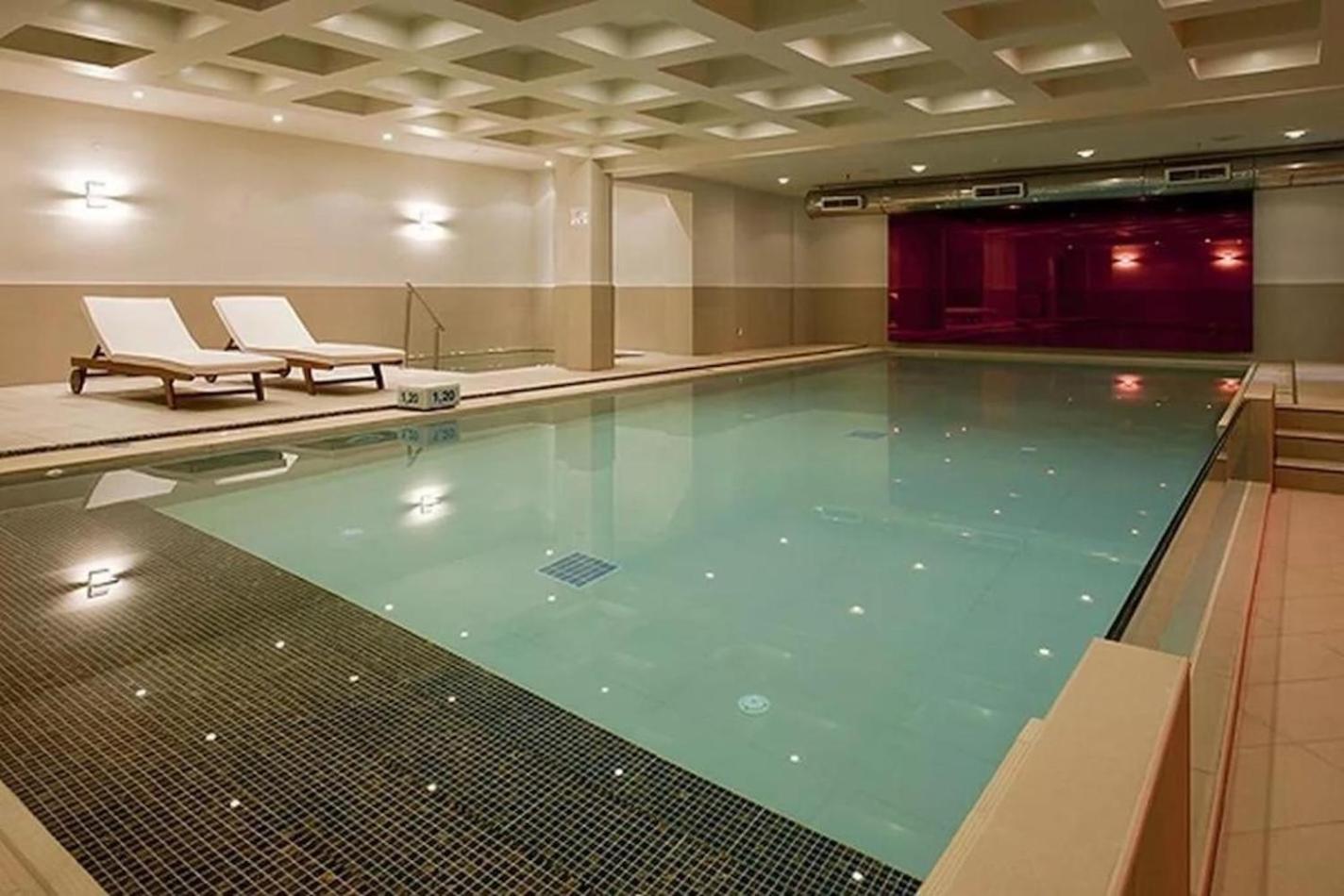 Pearl Beach spa centra iekštelpu baseins ar apsildi un atpūtas krēsliem — moderna relaksācijas zona ar dekoratīvu apgaismojumu