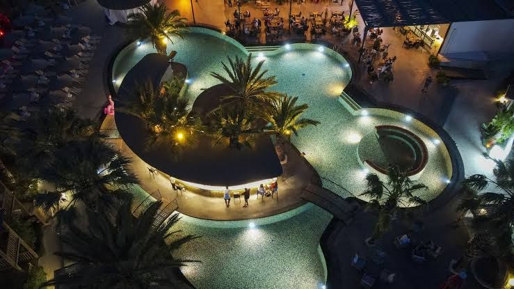 Vakara skats no augšas uz Otium Senses Very Chic Bodrum izgaismoto baseinu un bāru Gumbetā