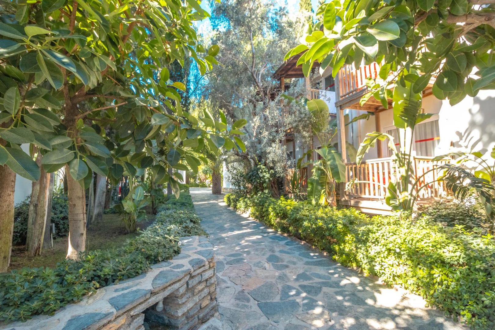 Otium Senses Very Chic Bodrum dārza celiņš starp zaļojošiem kokiem un numuru korpusiem ar koka balkoniem
