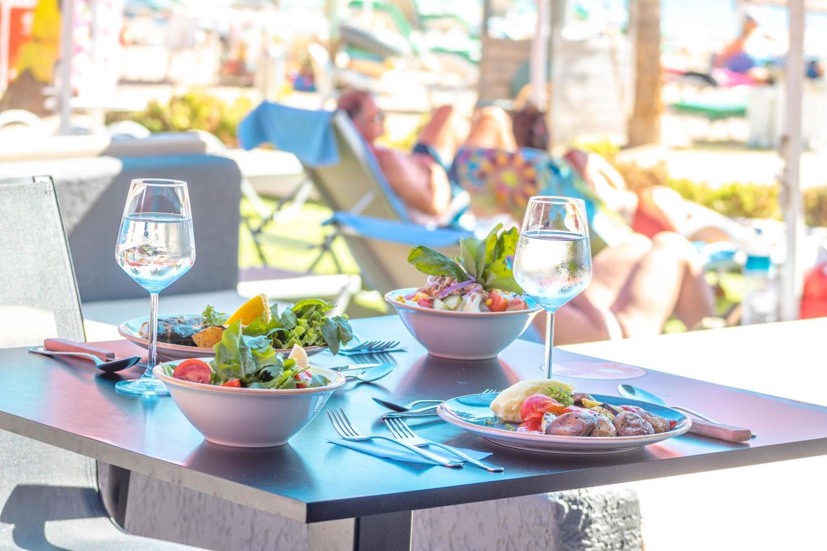 Pusdienu galds Otium Senses Very Chic Bodrum āra terasē ar svaigiem salātiem, grilētiem dārzeņiem un ūdens glāzēm saulainā dienā