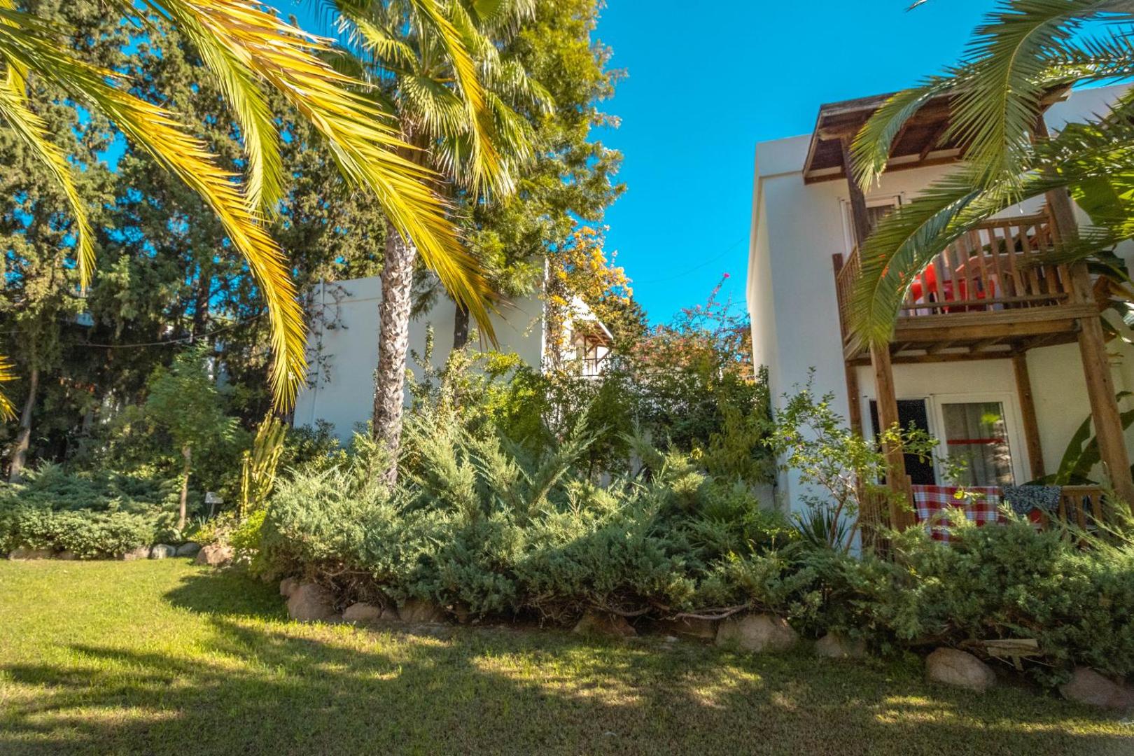 Otium Senses Very Chic Bodrum viesnīcas ēkas fasāde ar koka balkoniem un palmām saulainā dienā