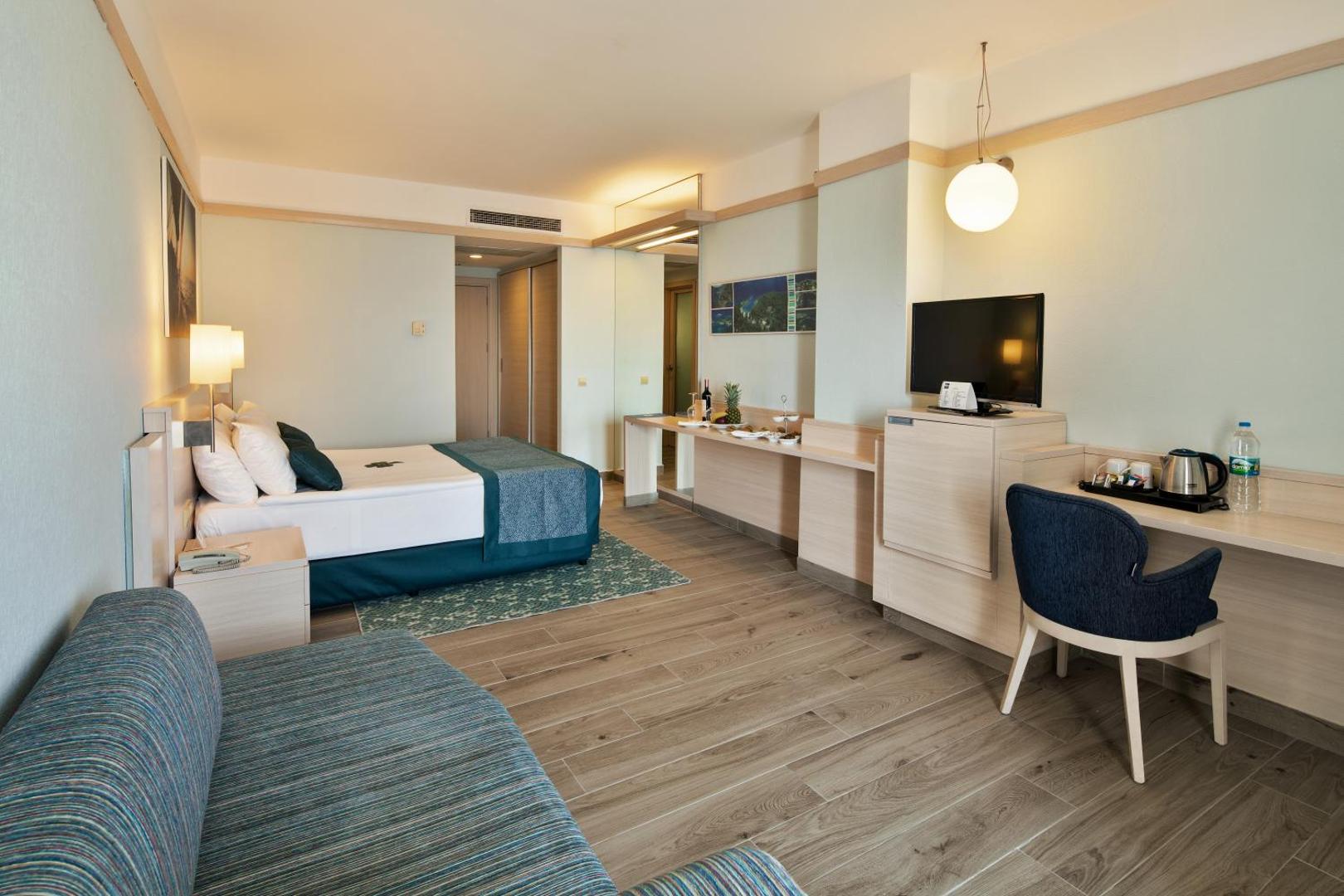La Blanche Resort & Spa plašs numurs ar gaišām koka mēbelēm, divguļamo gultu, dīvānu un darba zonu Bodrumas piekrastē