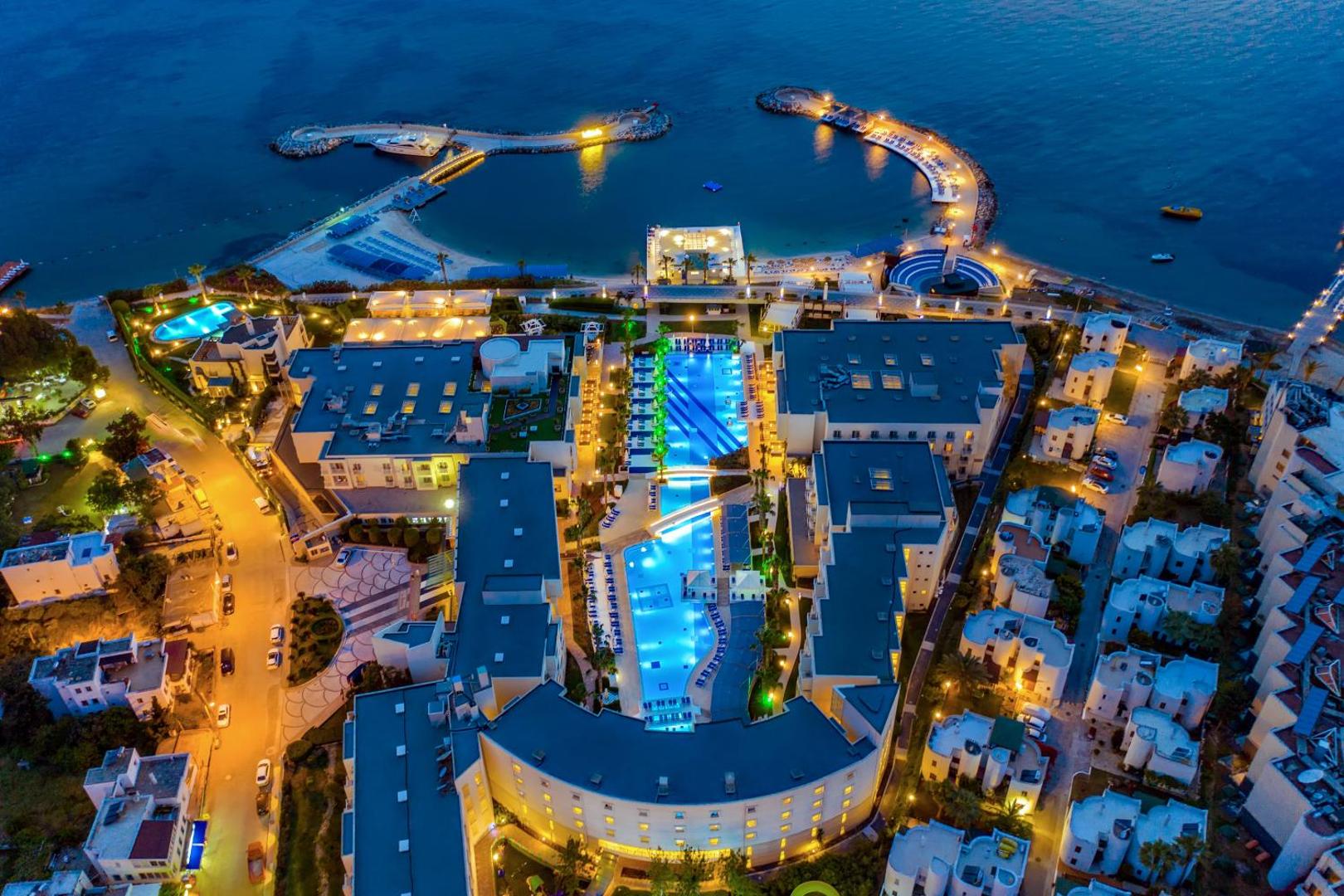 La Blanche Resort & Spa vakara skats no augšas uz izgaismoto baseinu kompleksu un viesnīcas korpusiem pie jūras