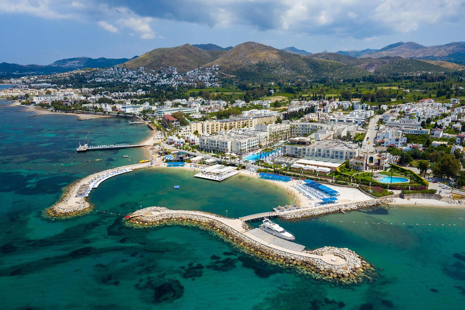 La Blanche Resort & Spa panorāmas skats no putna lidojuma uz piekrasti Bodrumā — tirkīza krāsas jūra, privātā pludmale un kalnu fons