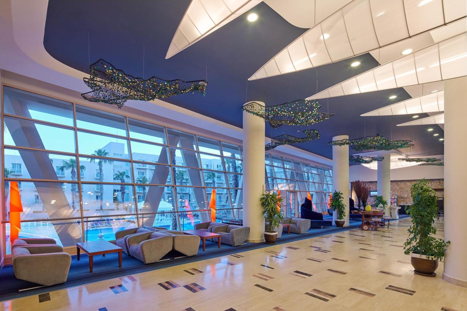La Blanche Resort & Spa plašais lobby ar panorāmas logiem, atpūtas zonu un skatu uz baseinu Turgutreisā, Bodrumā