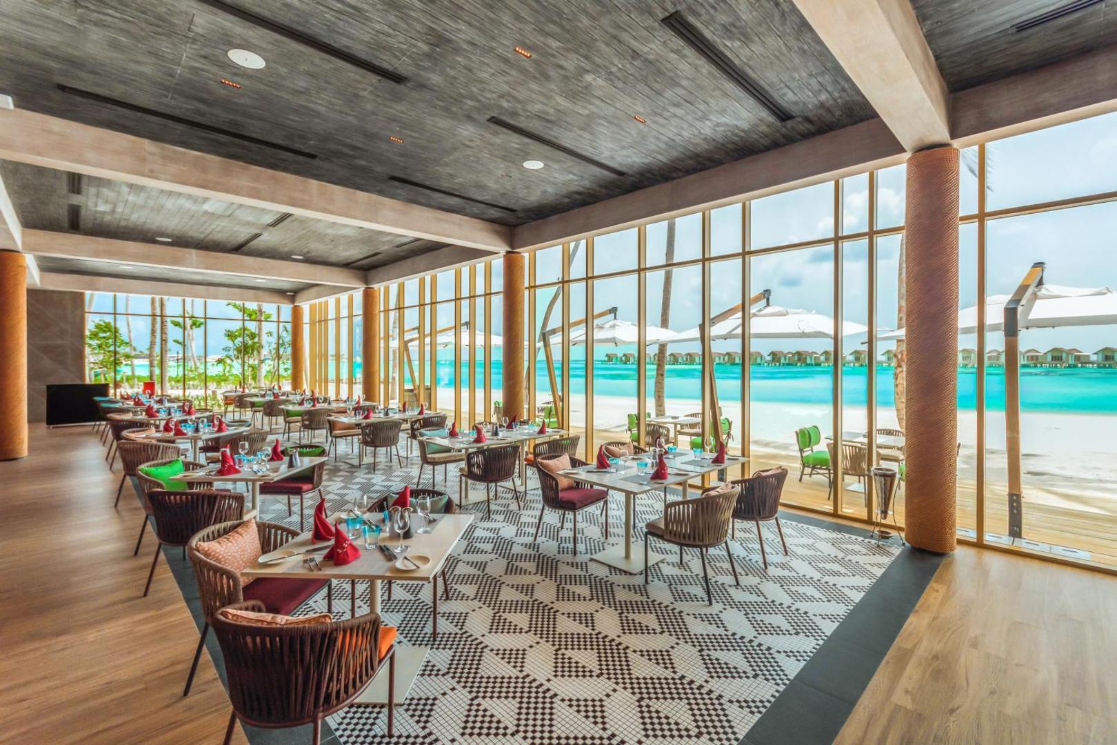 Hard Rock Hotel Maldives restorāna interjers ar lieliem panorāmas logiem, skatu uz pludmali un okeānu Maldīvās