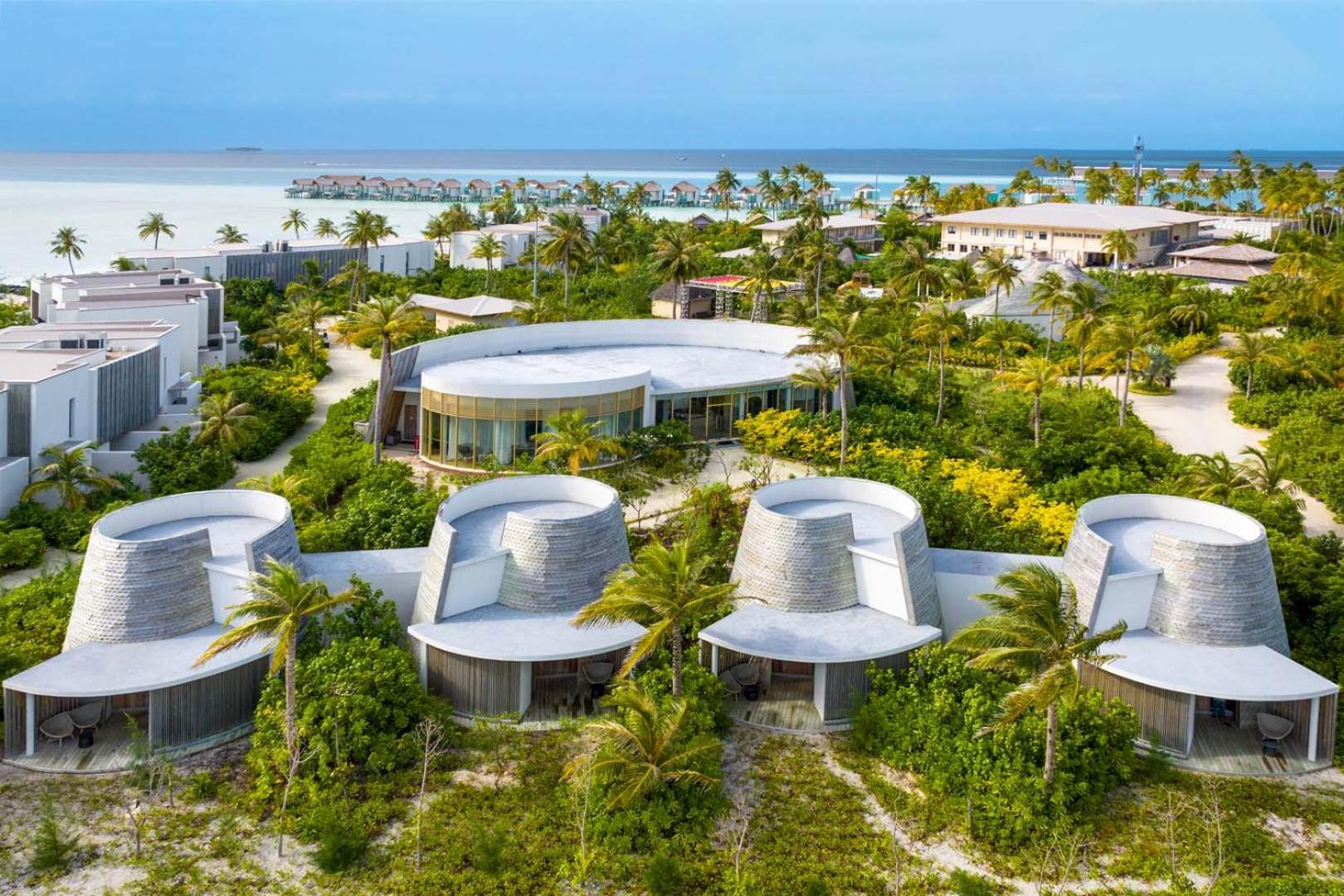 Hard Rock Hotel Maldives pludmales villas un modernā arhitektūra — zaļojošs dārzs ar palmām un kūrorta numuri Maldivu salās