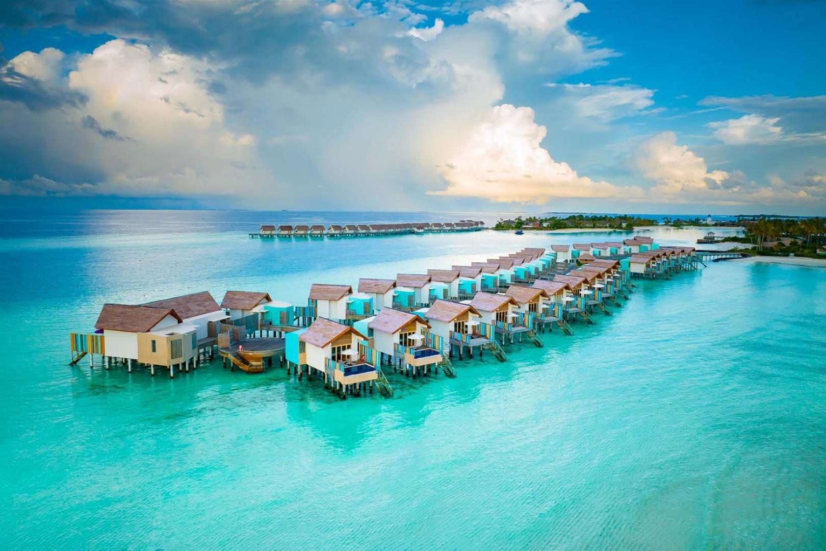 Hard Rock Hotel Maldives moderni ūdens bungalo ar baseiniem — tirkīzzils okeāns un debesis virs kūrorta Maldivu salās