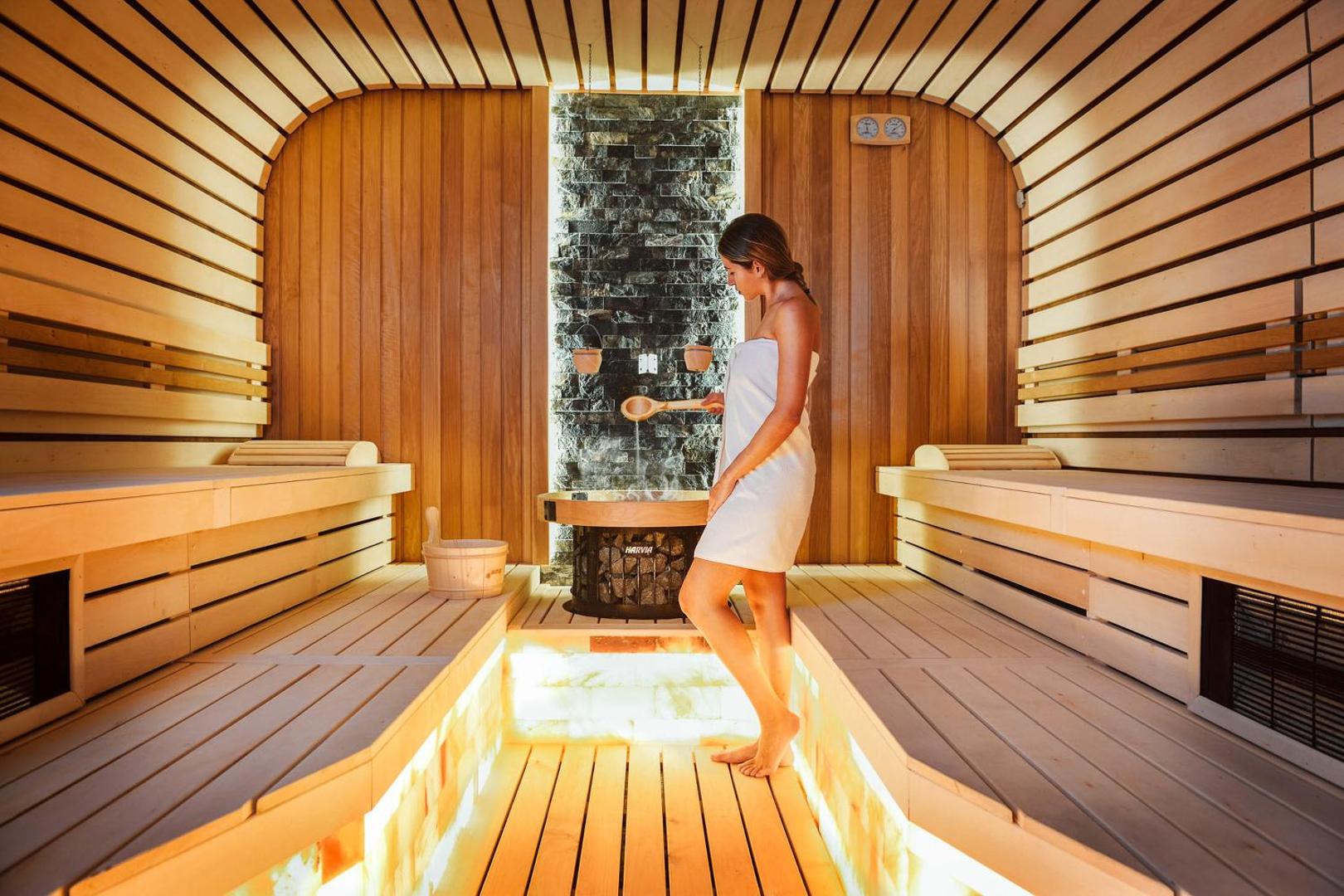 Moderna sauna ar koka apdari un sāls sienu Grifid Encanto Beach spa centrā, sieviete bauda relaksāciju