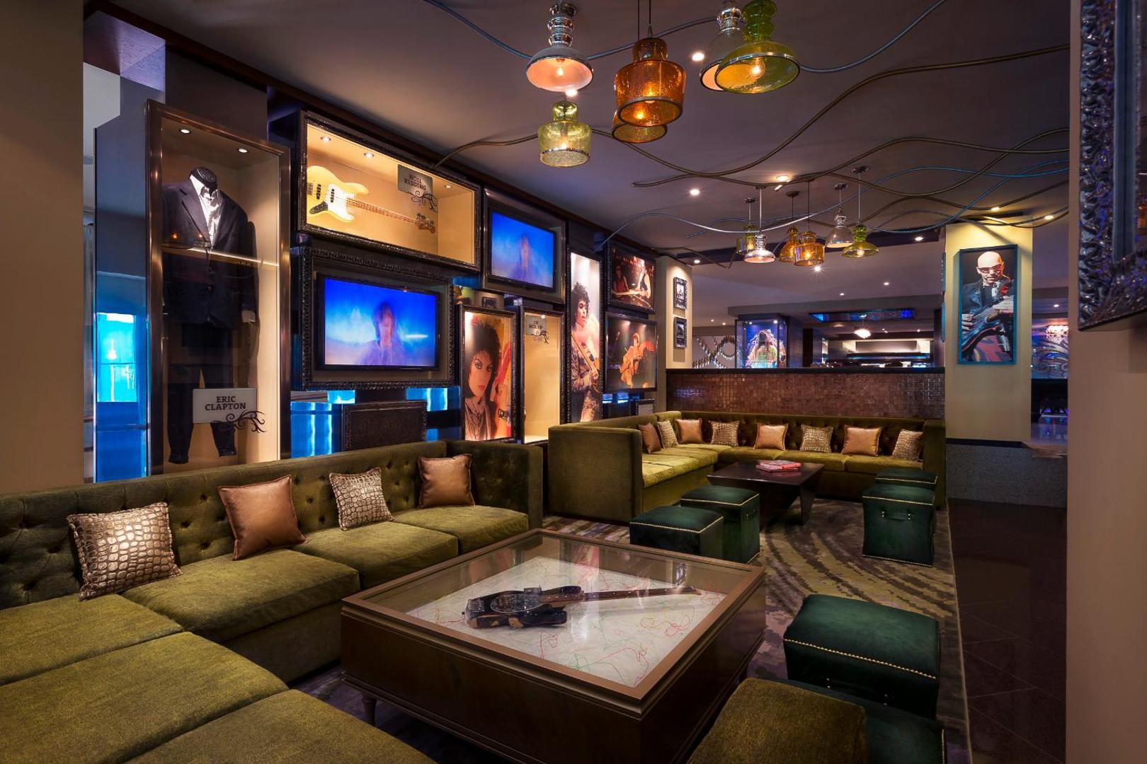 Hard Rock Hotel Cancun atpūtas telpa ar mīkstiem dīvāniem, mūzikas relikvijām pie sienām un stilīgiem gaismas ķermeņiem