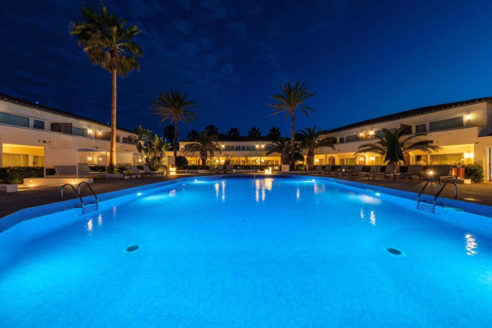 Oassium Hotel - Adults Only izgaismots āra baseins naktī ar palmu siluetiem un mājīgu apgaismojumu pie numuriem