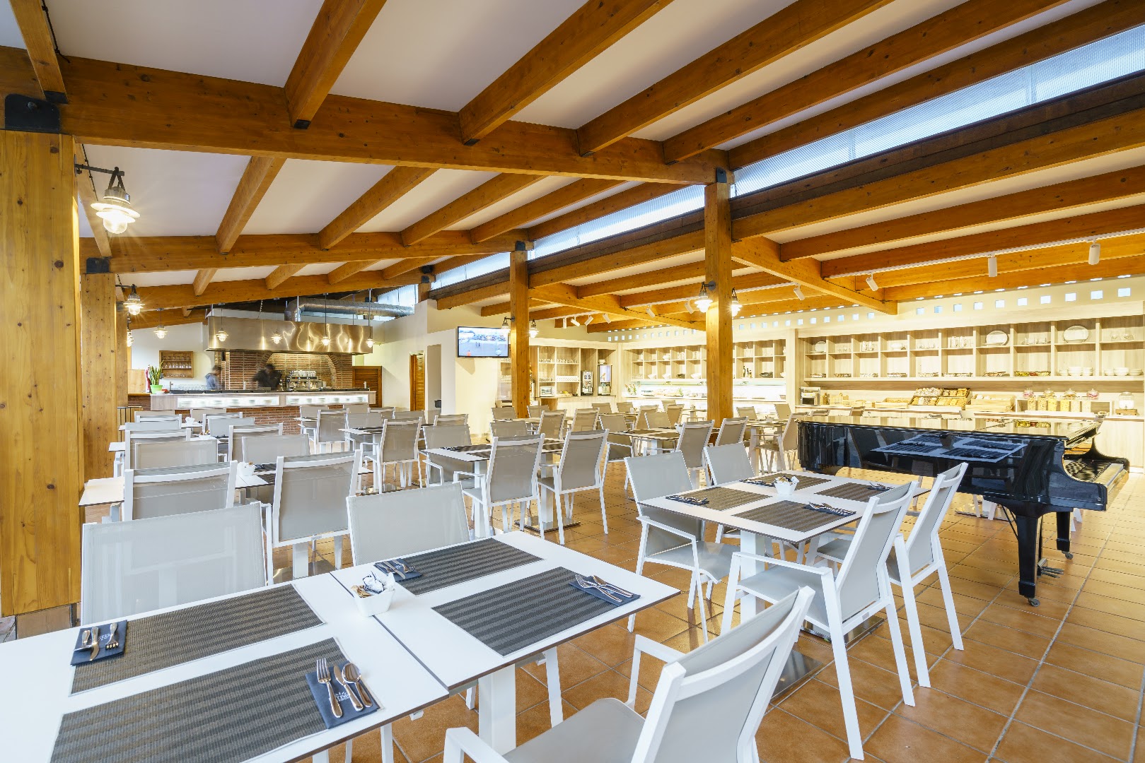 Oassium Hotel - Adults Only restorāna zāle ar koka sijām, gaišiem galdiem un flīžu grīdu, fonā redzams melns flīģelis