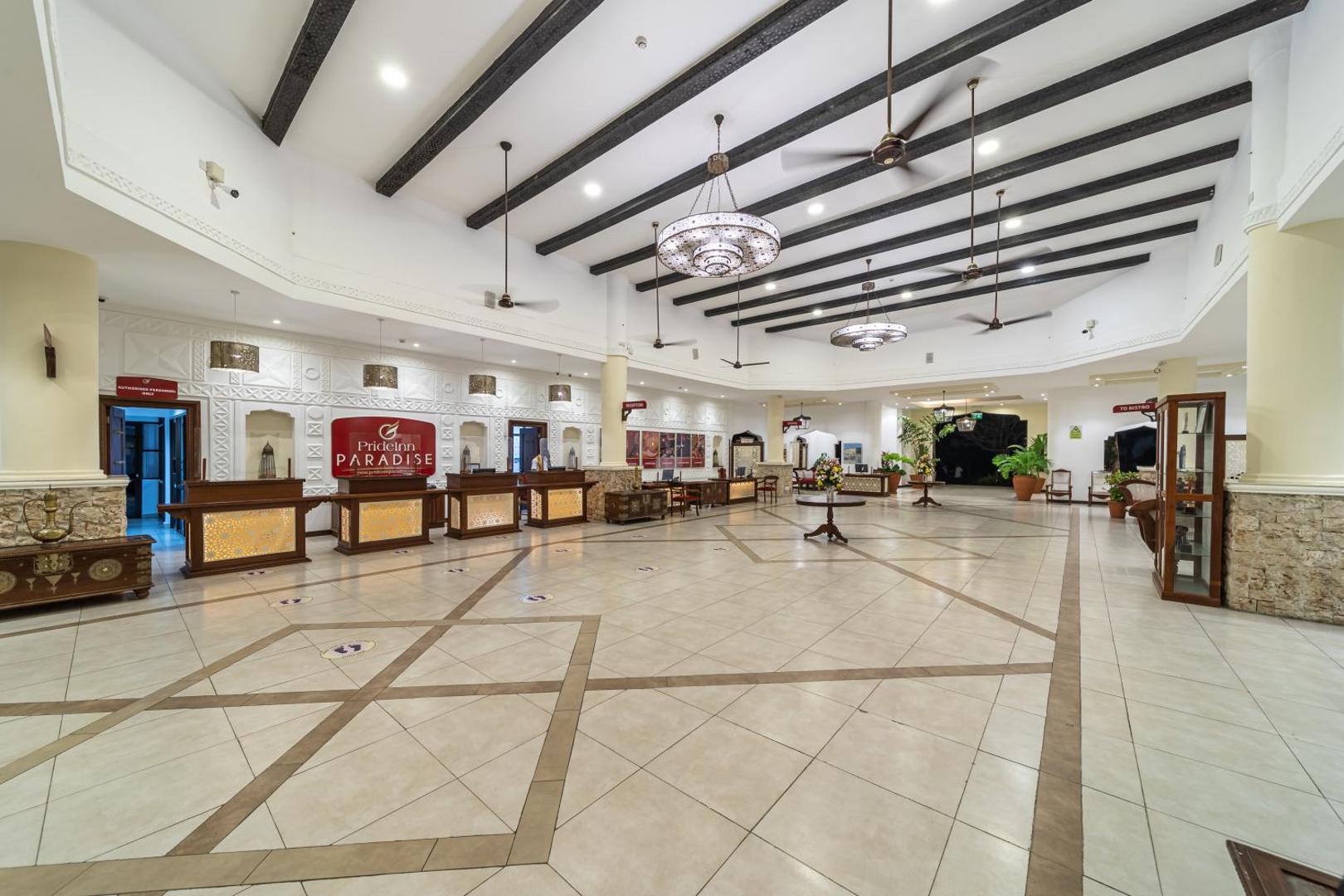 PrideInn Paradise Beach Resort & Spa plašā lobby zona ar recepcijas leti, augstiem griestiem un tradicionāliem dekoru elementiem