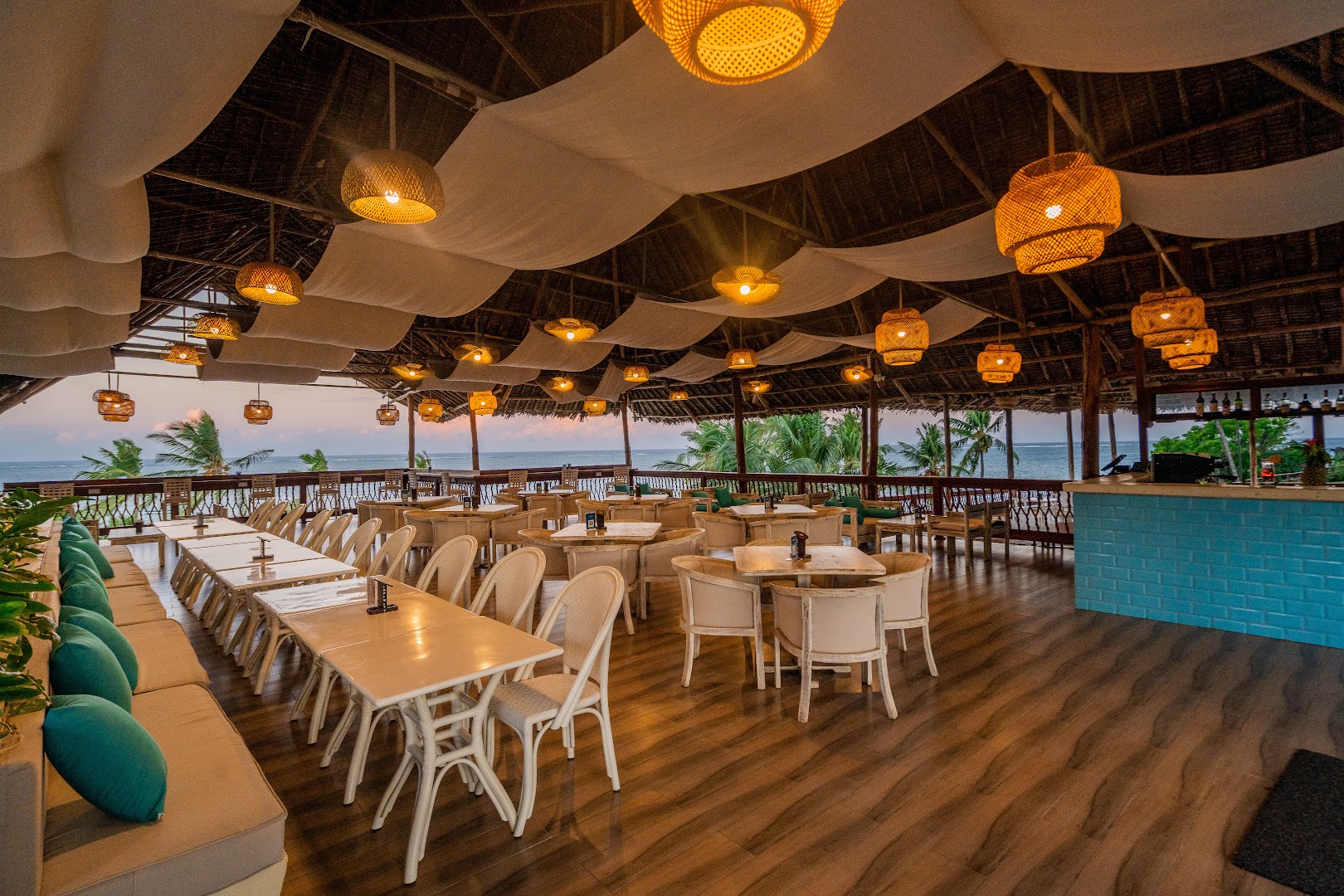 PrideInn Paradise Beach Resort & Spa atvērtā tipa restorāns ar skatu uz okeānu, pītiem gaismekļiem un koka mēbelēm