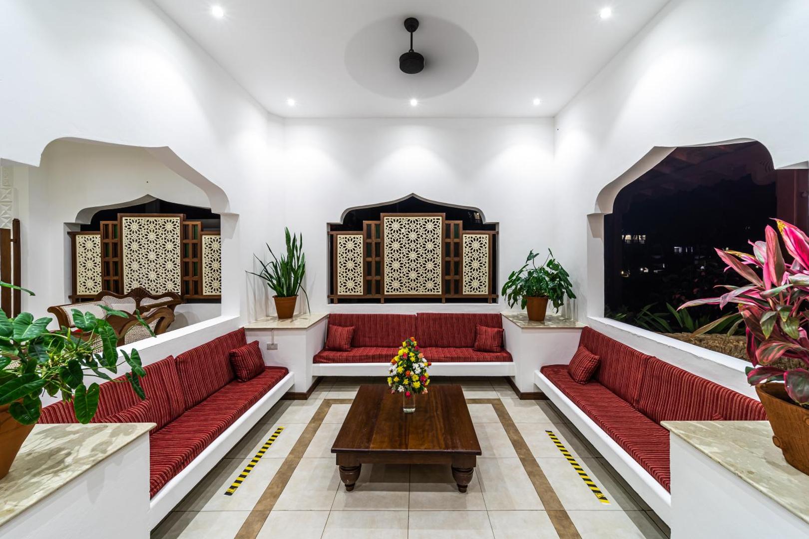 PrideInn Paradise Beach Resort & Spa Mombasa atpūtas zona ar sarkaniem dīvāniem, koka galdu un tradicionāliem austrumu stila sienas dekoriem