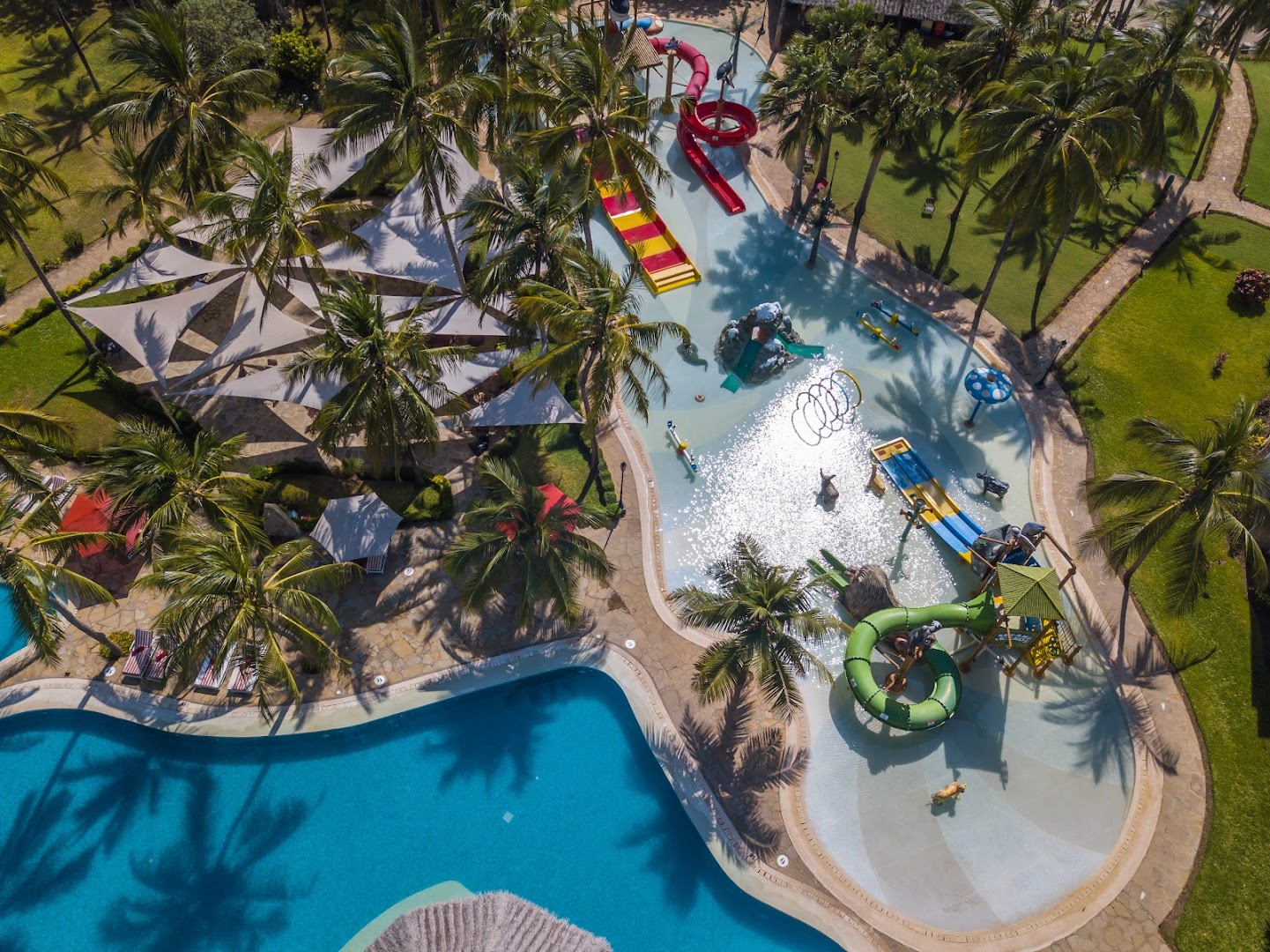 PrideInn Paradise Beach Resort & Spa bērnu akvaparks no putna lidojuma Mombasā — krāsaini slidkalniņi, sekls baseins un palmas