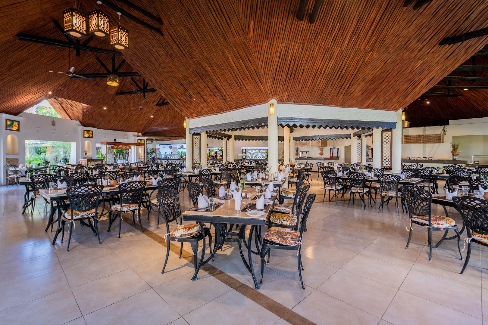 PrideInn Paradise Beach Resort & Spa galvenā restorāna zāle ar augstiem koka griestiem un eleganti klātiem galdiem