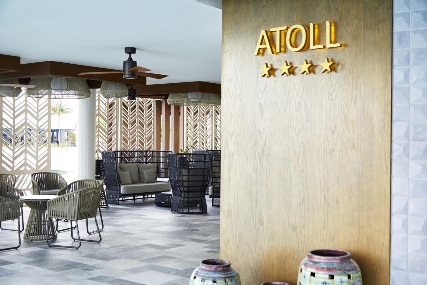 Hotel RIU Atoll 4* viesnīcas ieejas zona ar ērtiem atpūtas krēsliem, koka paneļiem un tropisku dizainu Maldīvās