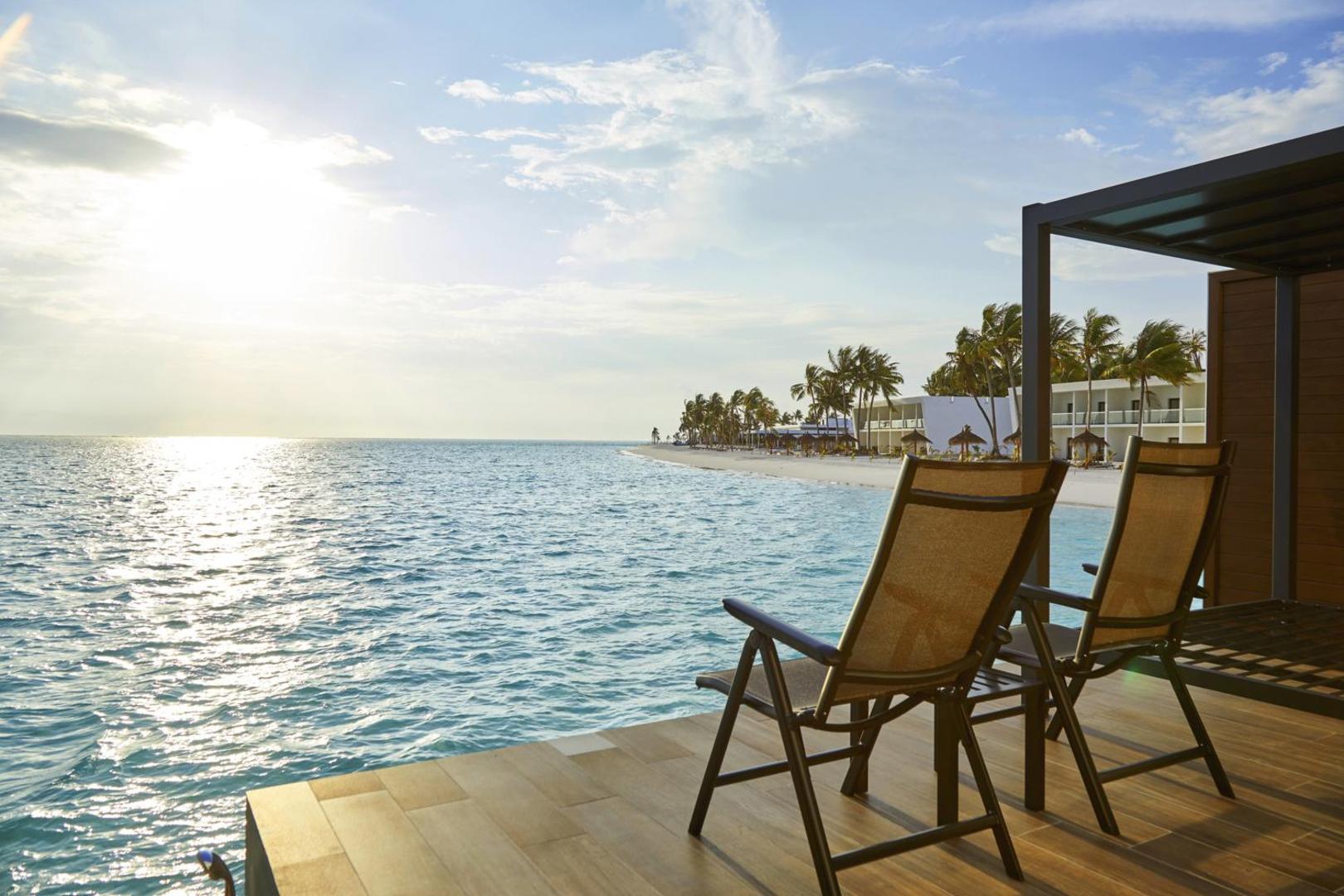 Hotel RIU Atoll terase virs ūdens ar sauļošanās krēsliem un skatu uz tirkīzzilo lagūnu un balto smilšu pludmali