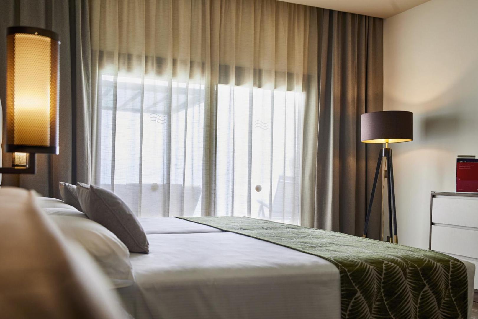 Hotel RIU Atoll numura detaļa ar gultu un mīkstu apgaismojumu vakara noskaņās Maldīvu salu viesnīcā