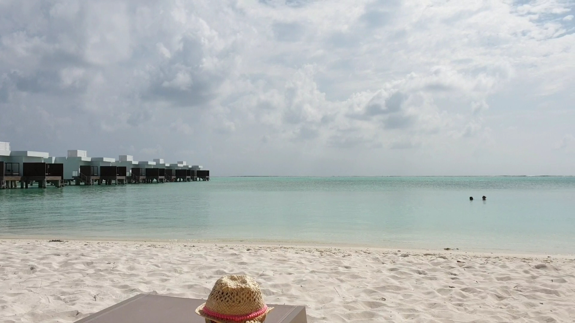 Hotel RIU Atoll ūdens bungalo virs tirkīza lagūnas Maldivu salās — skats no pludmales atpūtas zonas