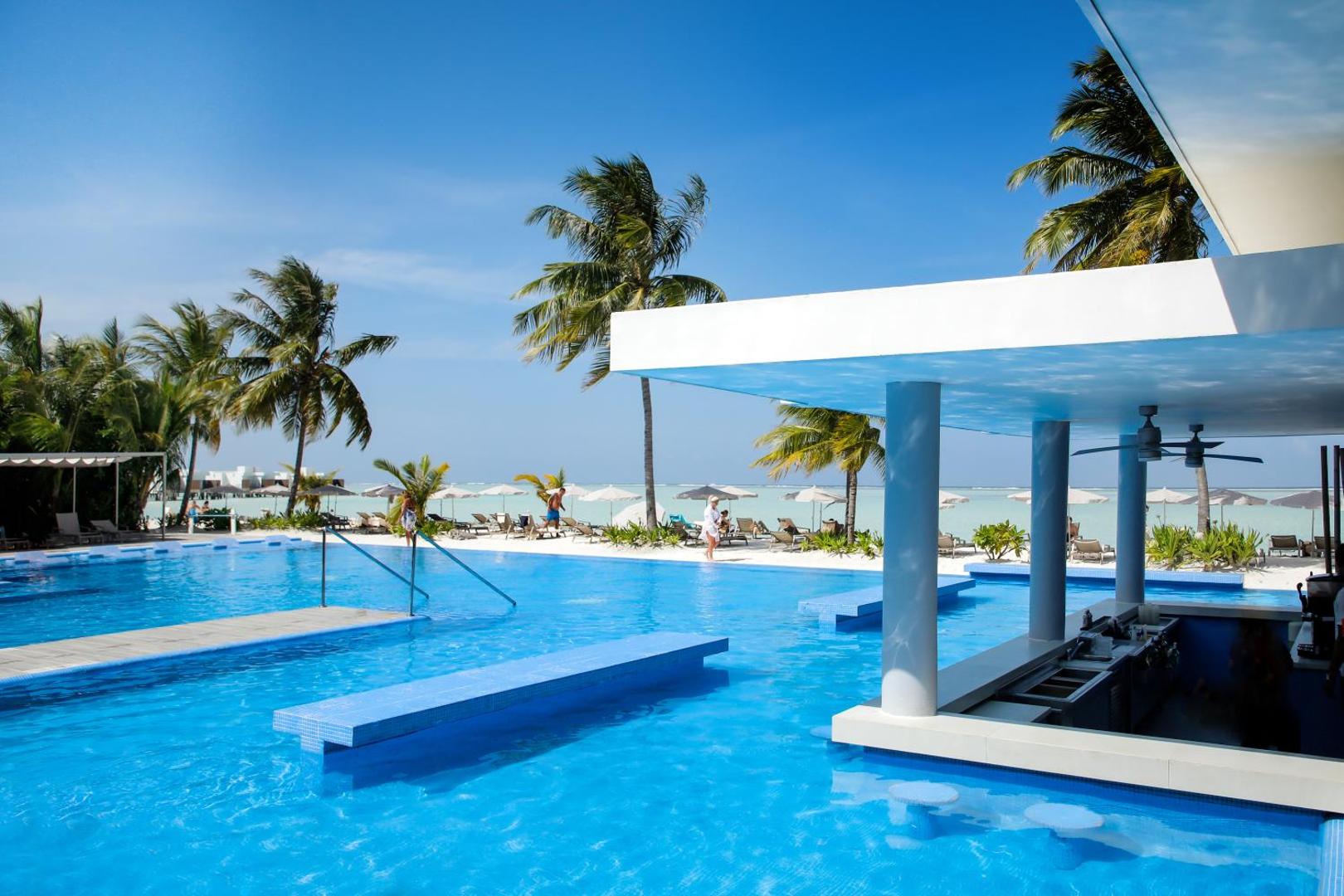 Hotel Riu Atoll baseina bārs ar sēdvietām ūdenī, skats uz tirkīzzilo okeānu un balto smilšu pludmali