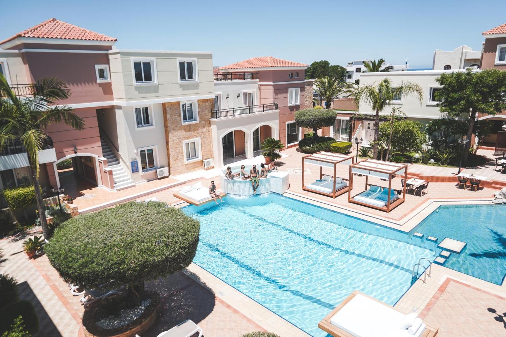 Viesi atpūšas pie Zeus Hotels The Village Resort & Waterpark baseina un džakuzi zonas saulainā dienā Krētā