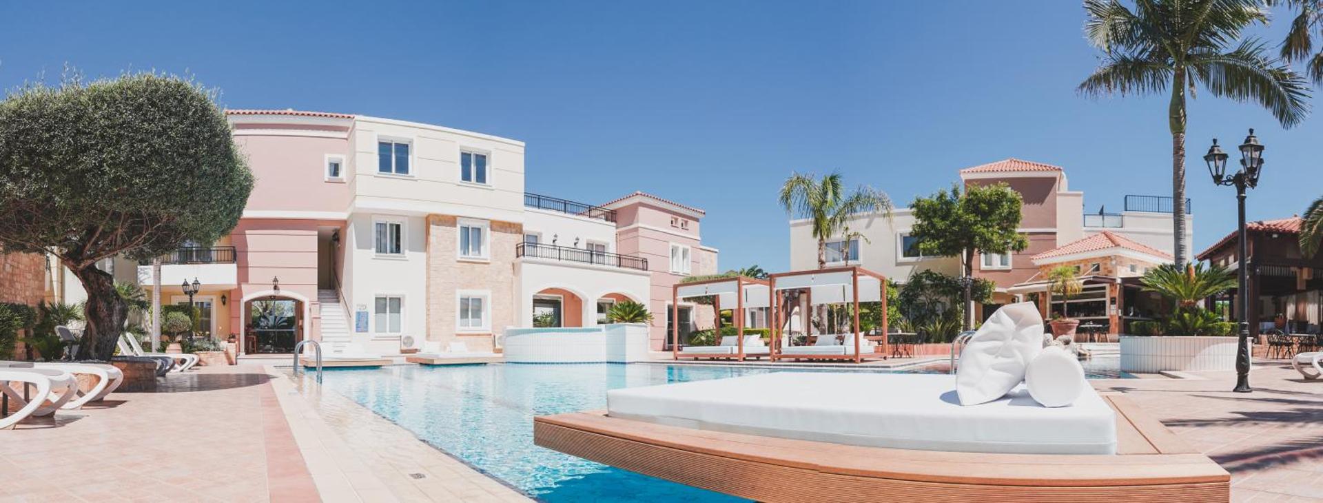 Zeus Hotels The Village Resort & Waterpark baseina zona ar moderniem atpūtas zviļņiem un viesnīcas korpusiem fonā Hersonisā
