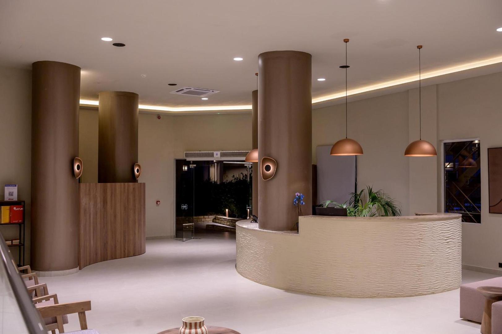 Zeus Hotels Ydoria Resort viesnīcas recepcijas zona ar modernu dizainu, apaļām kolonnām un siltu, mājīgu apgaismojumu vakarā