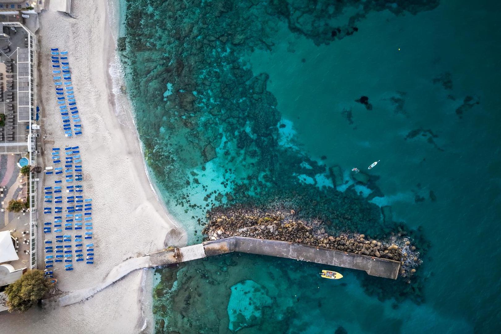 Annabelle Beach Resort skats no putna lidojuma uz dzidri zilo jūru, smilšu pludmali un akmens piestātni Hersonisā, Krētā
