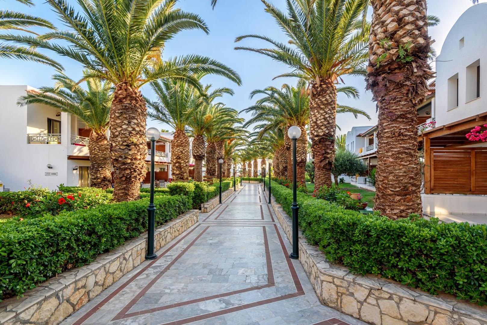 Annabelle Beach Resort labiekārtota gājēju eja ar palmām un ziedošiem krūmiem starp viesnīcas bungalo korpusiem.