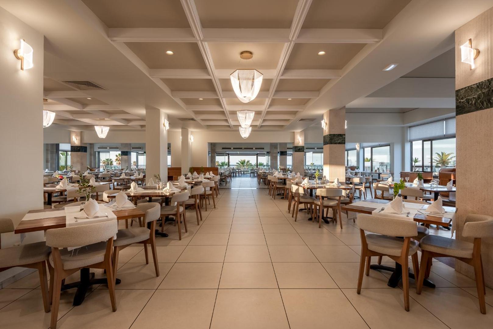 Plašs un gaišs Annabelle Beach Resort iekštelpu restorāns ar modernām lustrām, koka galdiem un lieliem logiem
