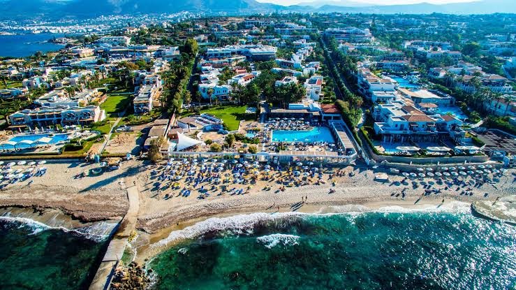 Annabelle Beach Resort aerofoto ar privāto pludmali, saulessargiem un piekrastes līniju Hersonisas reģionā.