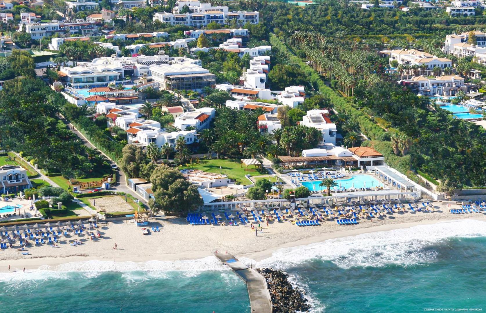 Annabelle Beach Resort panorāmas skats no putna lidojuma uz pludmali, baseiniem un balto bungalo kompleksu Krētā.