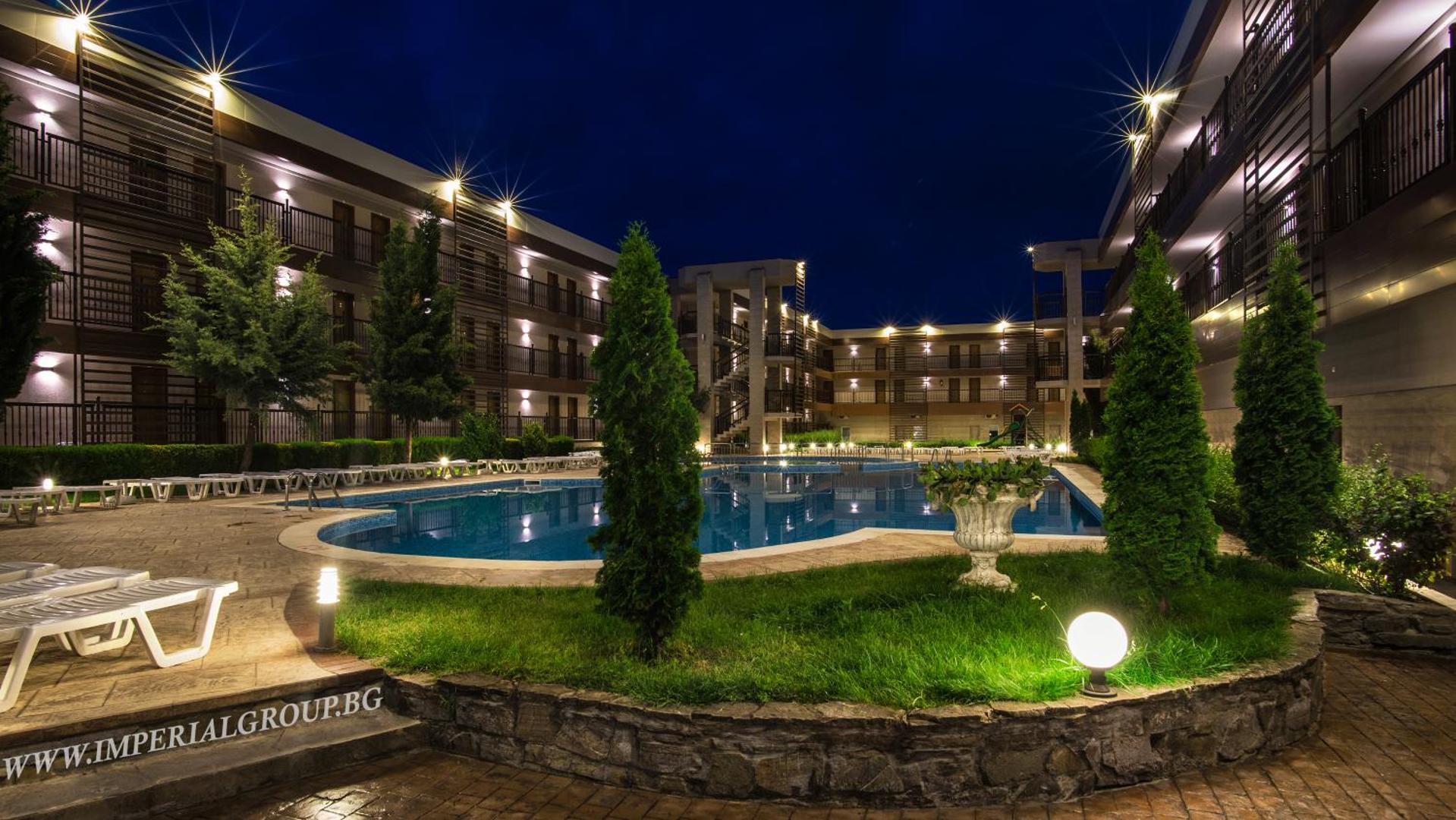 Imperial Resort iekšpagalms naktī ar apgaismotu baseinu, koptu zālienu, dekoratīviem kokiem un viesnīcas korpusiem apkārt