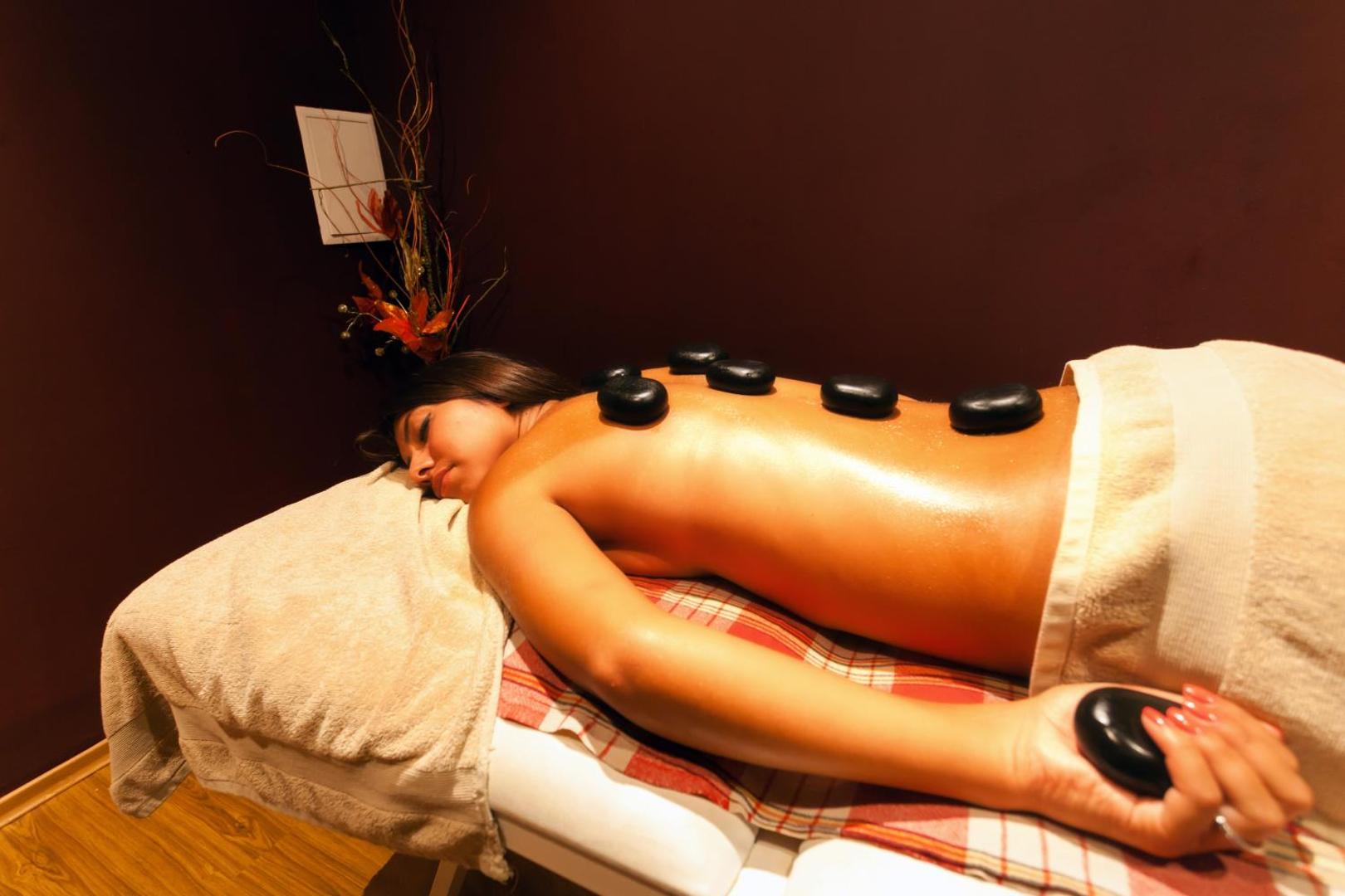 Sieviete bauda karsto akmeņu masāžu Imperial Resort spa centrā — relaksējoša atmosfēra ar sveču gaismu un profesionālu servisu