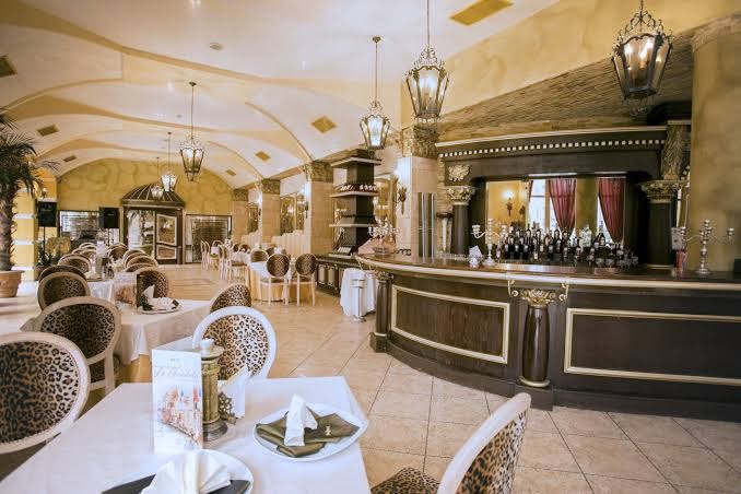 Viesnīcas Imperial Resort restorāns ar klasisku interjeru, bāra leti, greznām lustrām un galdiem ar leopardu raksta krēsliem