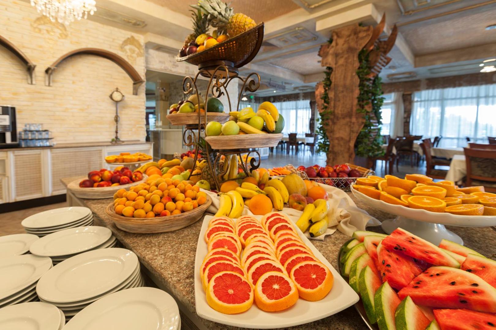 Imperial Resort bufetes restorāna augļu galds ar arbūziem, greipfrūtiem, banāniem un aprikozēm, kas sakārtoti vairākos līmeņos.