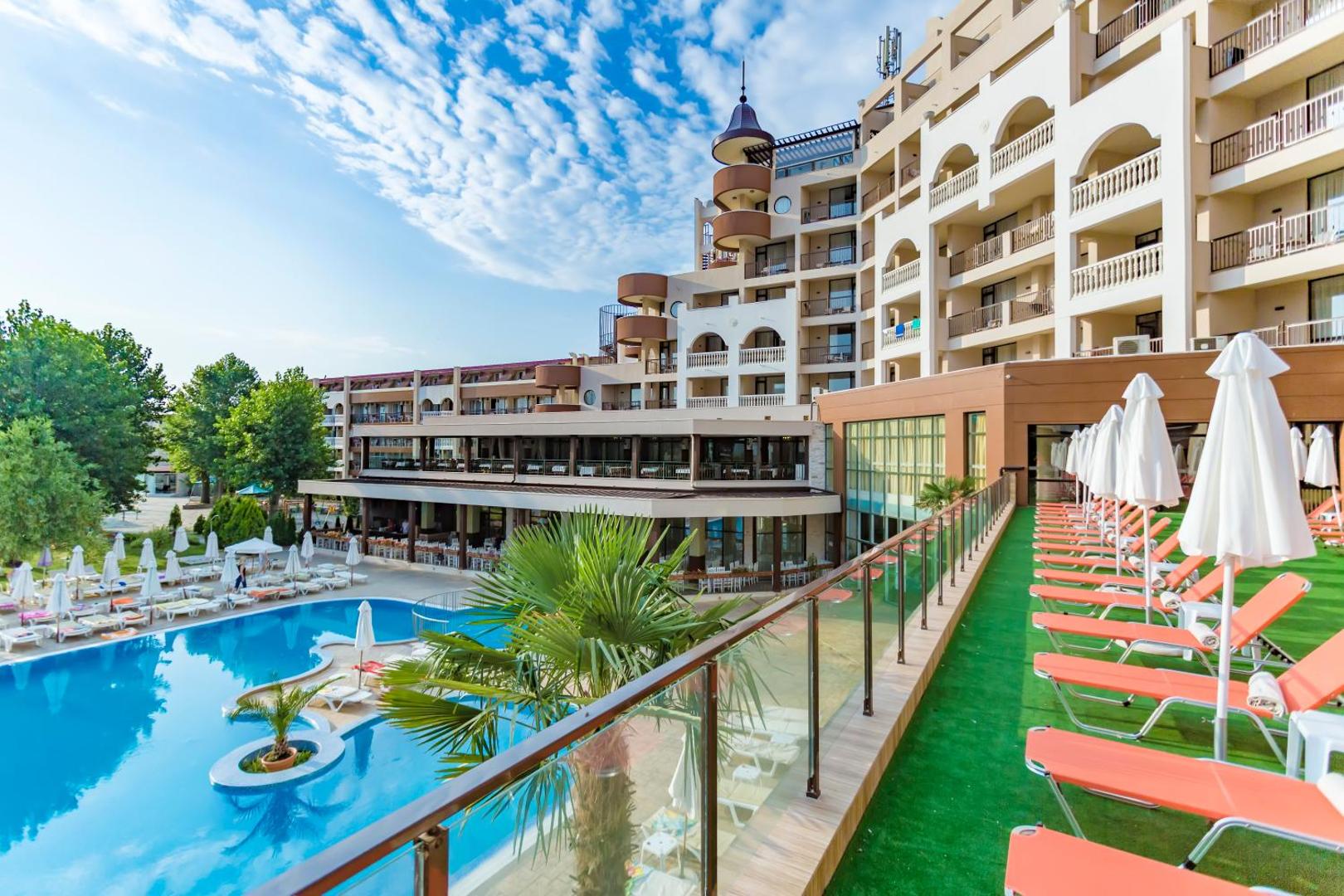 Imperial Resort viesnīcas ēkas fasāde ar balkoniem, āra baseinu un terasi ar oranžiem sauļošanās krēsliem un baltiem saulessargiem