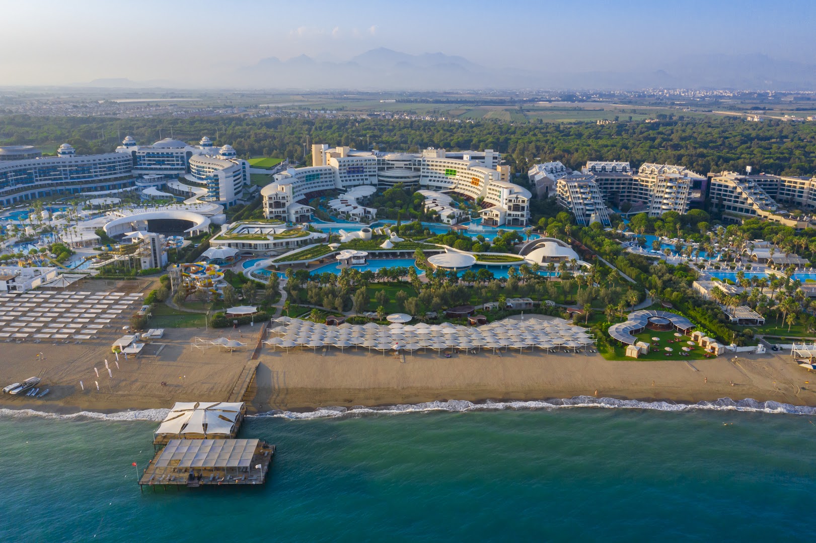 Cornelia Diamond Golf Resort & Spa panorāmas skats no putna lidojuma uz privāto pludmali, piestātni un viesnīcas kompleksu Belekā