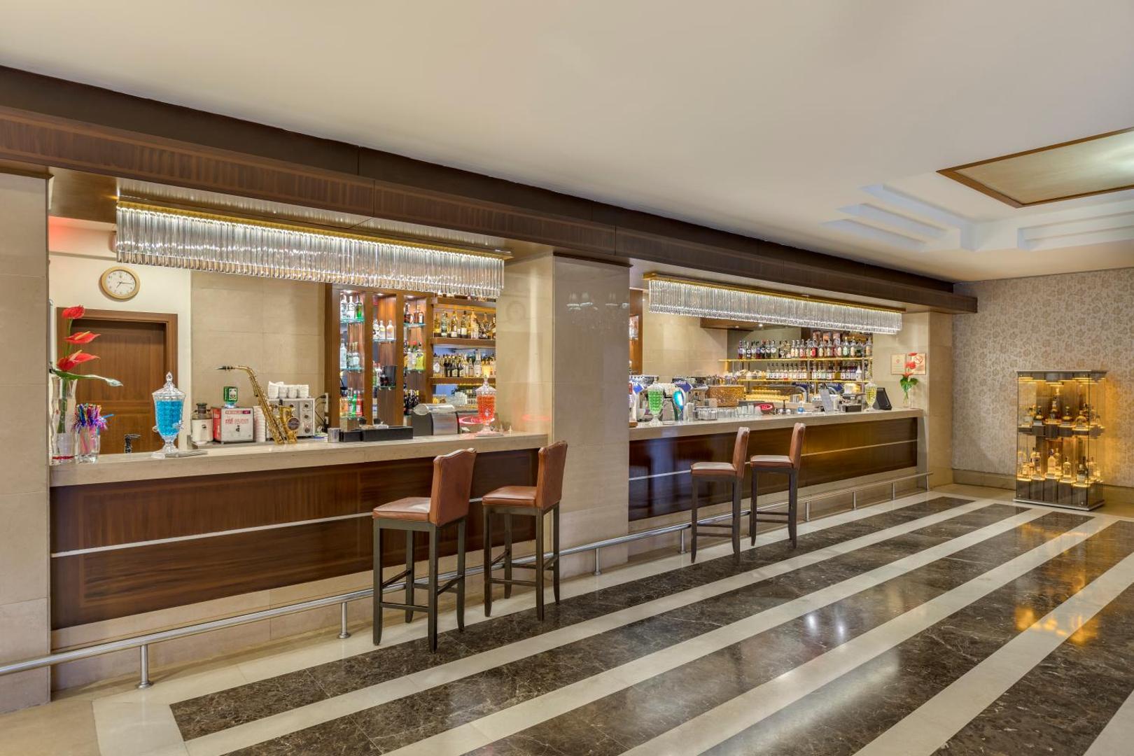 Dobedan Exclusive Hotel & Spa klasiskais bārs ar koka apdari un plašu dzērienu izvēli — bāra lete ar augstajiem krēsliem