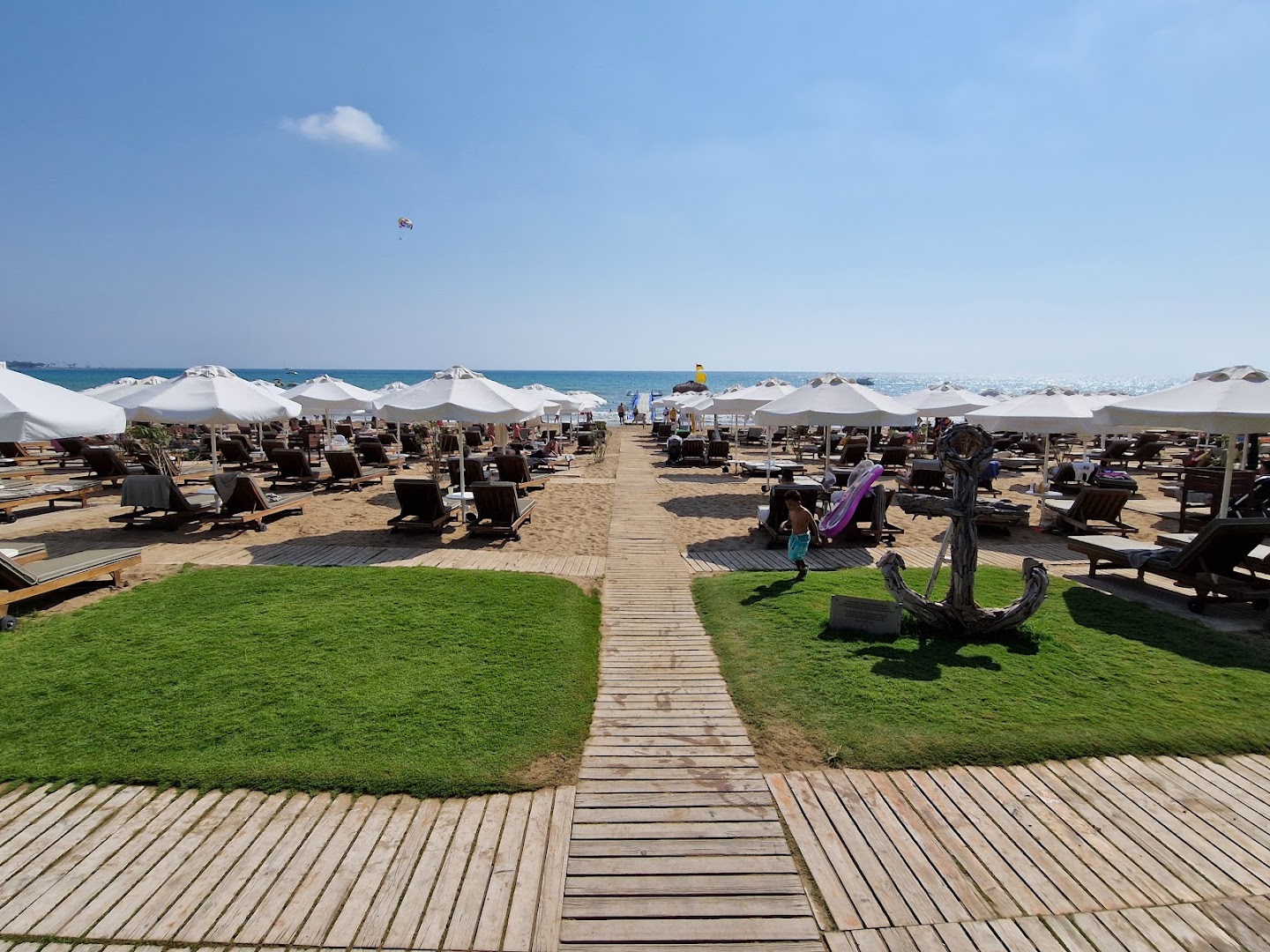 Barut Hemera viesnīcas privātā smilšu pludmale Sidē ar saulessargiem, sauļošanās krēsliem un koka laipām Vidusjūras krastā