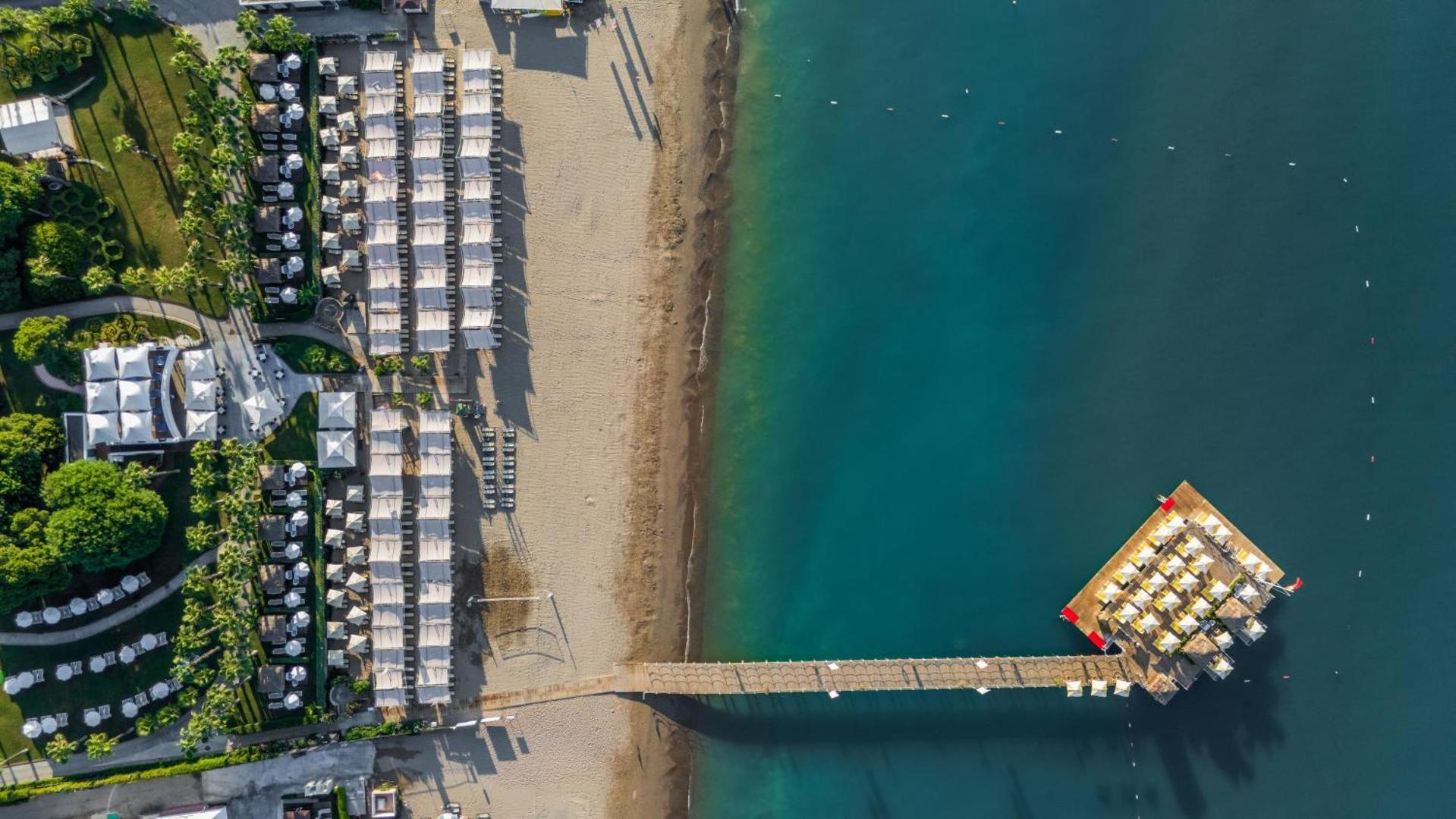Limak Atlantis De Luxe Hotel & Resort privātā pludmale un koka piestātne ar saulessargiem Belekā no augšas
