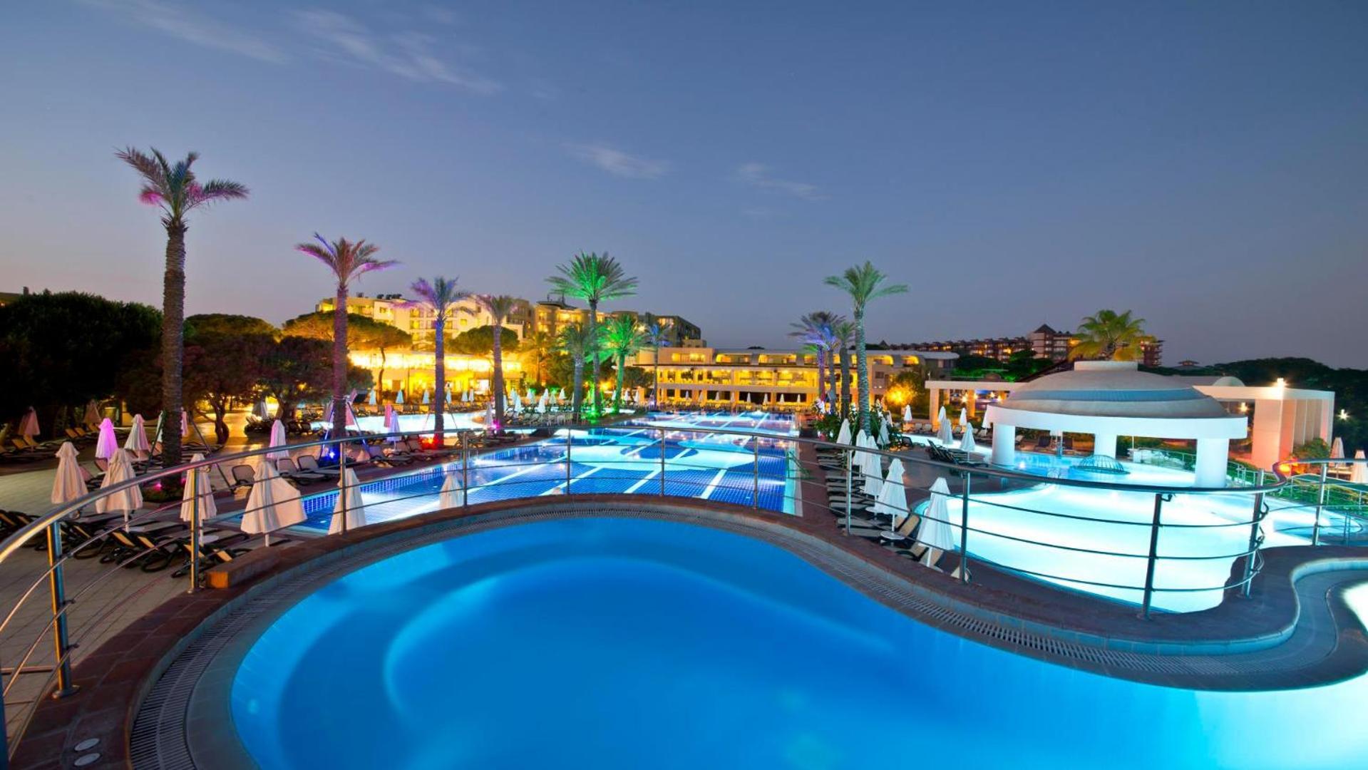 Limak Atlantis De Luxe Hotel & Resort izgaismoti baseini vakarā ar tiltiņiem un bāru pie ūdens Belekas kūrortā