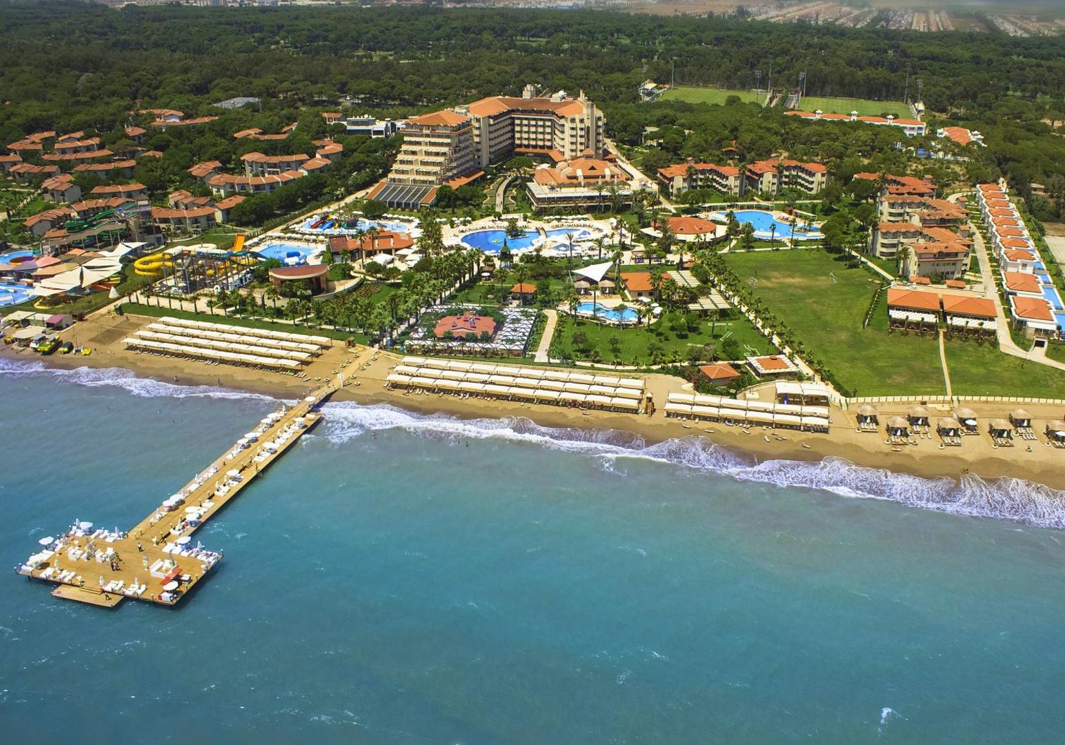 Bellis Deluxe Hotel Belekā no putna lidojuma — plaša teritorija ar baseiniem, privātu pludmali, koka piestātni un priežu mežu fonā